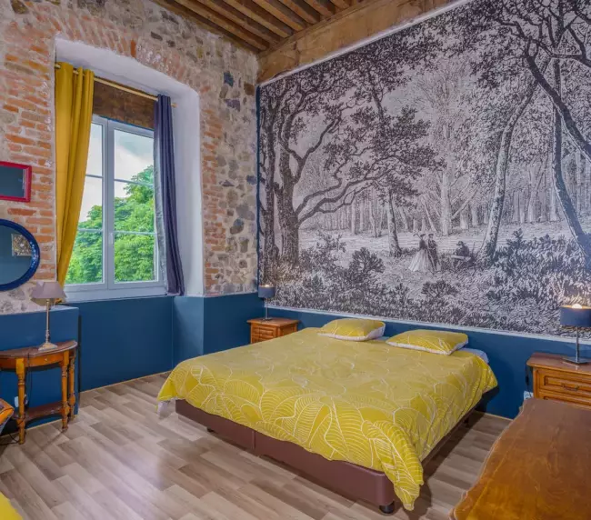 Chambre double du Château de Gorze – lit double, papier peint forêt et mur en brique apparente