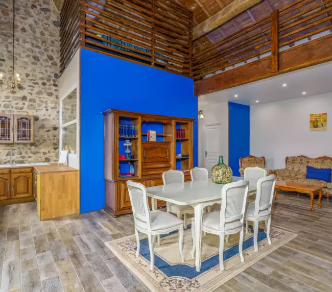 Séjour et salle à manger du gîte du Château de Gorze – espace double hauteur avec mezzanine et mur en pierre