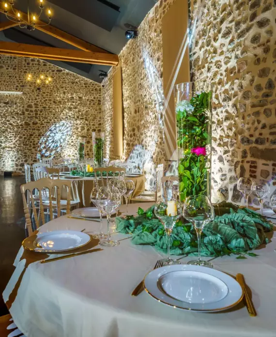 Salle de réception du Château de Gorze en configuration conférence – éclairage d'ambiance, mur en pierre apparente et charpente en bois