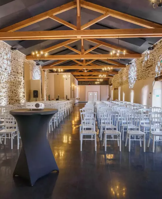 Salle de réception du Château de Gorze en configuration séminaire – vidéoprojecteur, chaises Napoléon et mur en pierre apparente