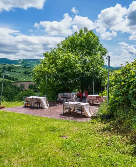Terrasse en bois du Château de Gorze dressée pour un repas en extérieur – guirlandes lumineuses et vue sur la campagne