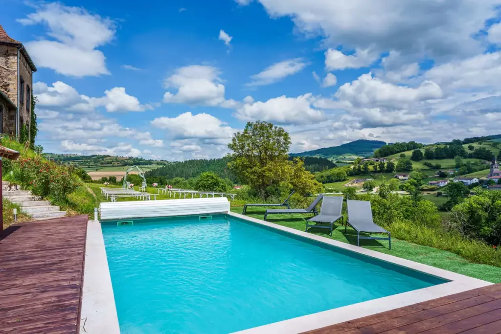Piscine du Château de Gorze avec transats et vue panoramique sur la vallée verdoyante