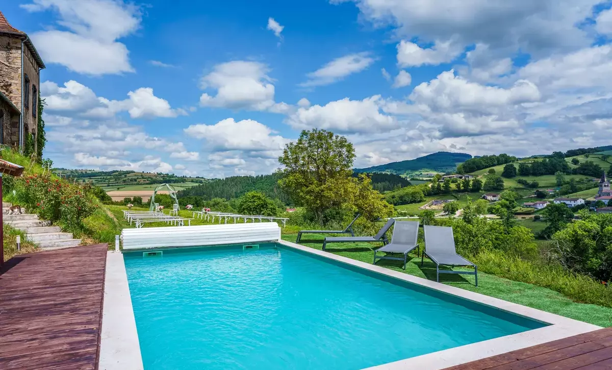 Piscine du Château de Gorze avec transats et vue panoramique sur la vallée verdoyante