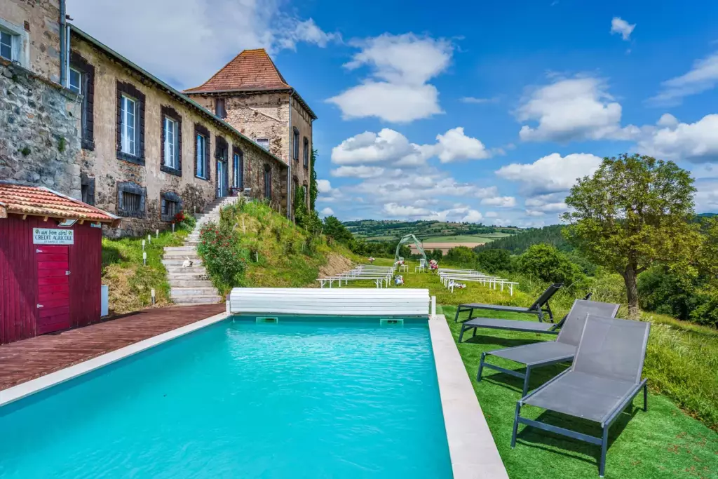 Piscine extérieure du Château de Gorze avec tour médiévale en arrière-plan et vue sur la campagne