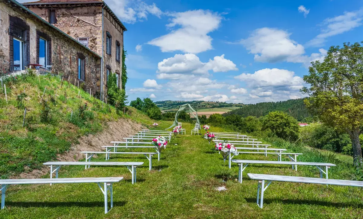 Cérémonie laïque en plein air au Château de Gorze – allée de bancs blancs fleuris et façade en pierre du château