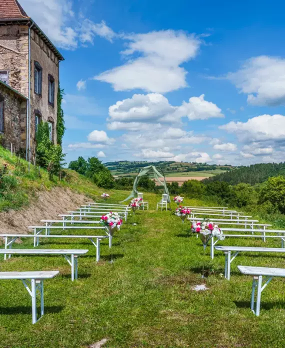 Cérémonie laïque en plein air au Château de Gorze – allée de bancs blancs fleuris et façade en pierre du château