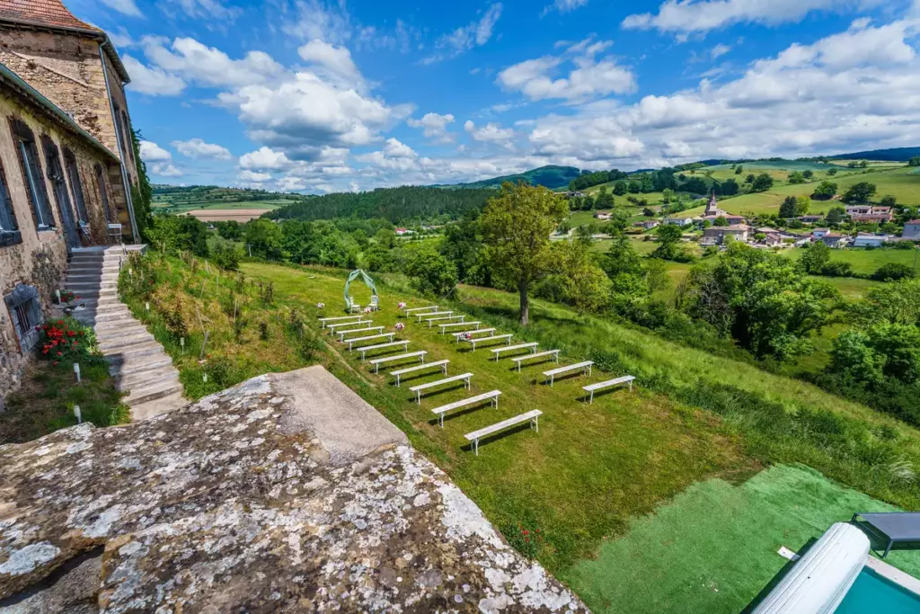 Cérémonie laïque en plein air au Château de Gorze – bancs blancs, arceau floral et vue dégagée sur la campagne