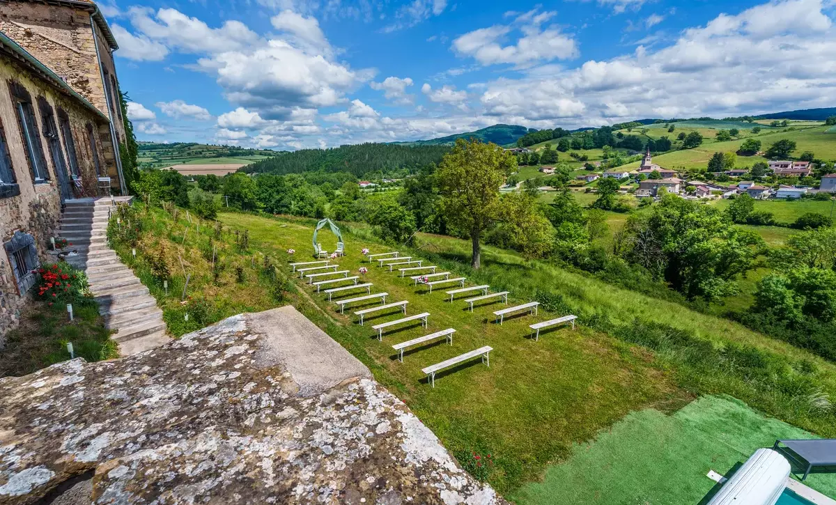 Cérémonie laïque en plein air au Château de Gorze – bancs blancs, arceau floral et vue dégagée sur la campagne