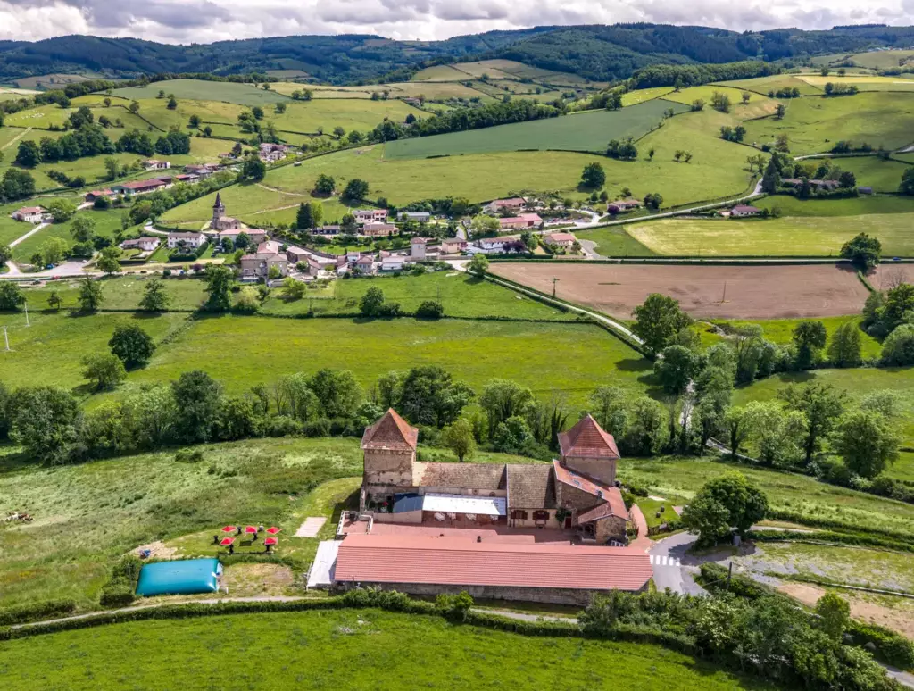 Vue aérienne lointaine du Château de Gorze dans son environnement rural – village et collines en arrière-plan