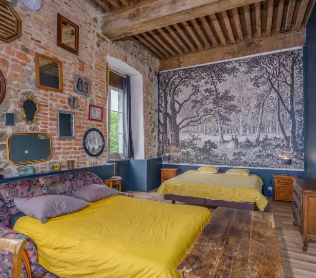 Chambre familiale du Château de Gorze avec deux lits, papier peint forêt panoramique et poutres apparentes