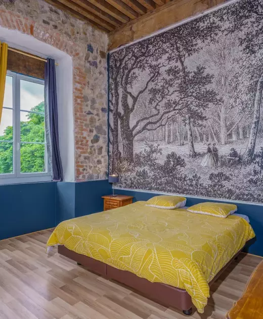 Chambre double du Château de Gorze – lit double, papier peint forêt et mur en brique apparente