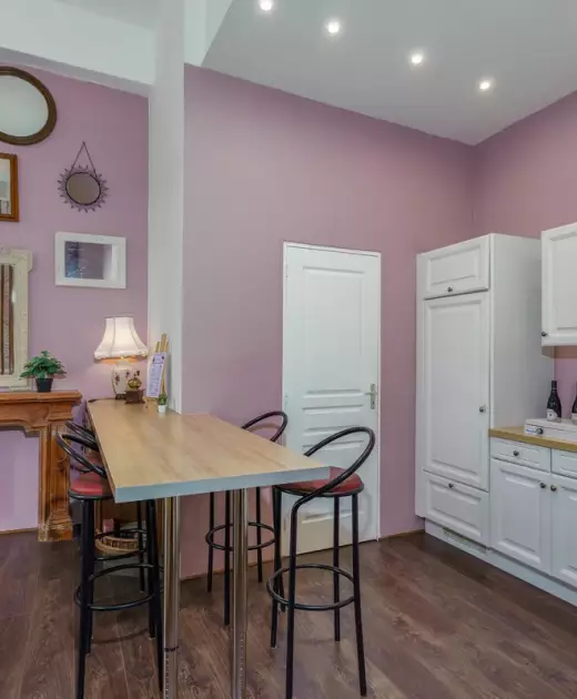 Cuisine équipée du gîte du Château de Gorze – bar avec tabourets, façades blanches et mur mauve